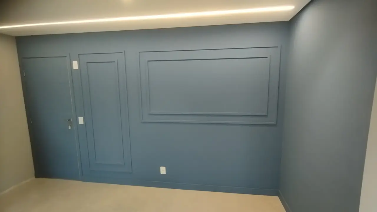 Parede azul com boiserie e iluminação indireta